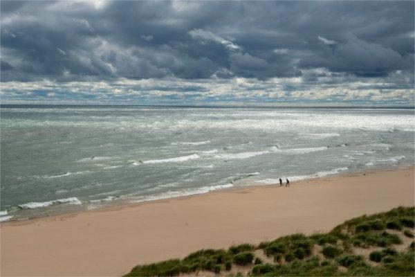 Two people walk the beach along Lake Michigan.